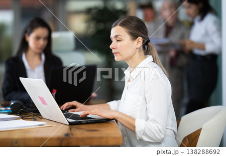Focused middle-aged woman working on laptop during busy corporate session Focused middle-aged woman working on laptop during busy corporate session 138288692