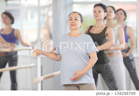 Senior woman practicing battement tendu in beginner ballet class 138288789