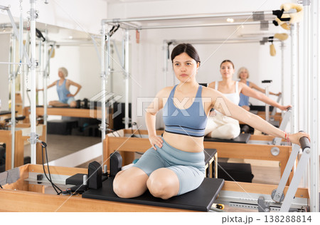 Young positive woman doing Pilates on special equipment in gym Young positive woman doing Pilates on special equipment in gym 138288814