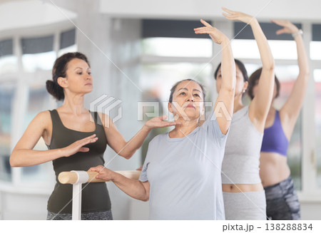 Adult woman teacher correcting beginning dancers Adult woman teacher correcting beginning dancers 138288834