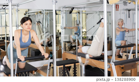 Young asian girl performing pilates exercises on reformer Young asian girl performing pilates exercises on reformer 138288900