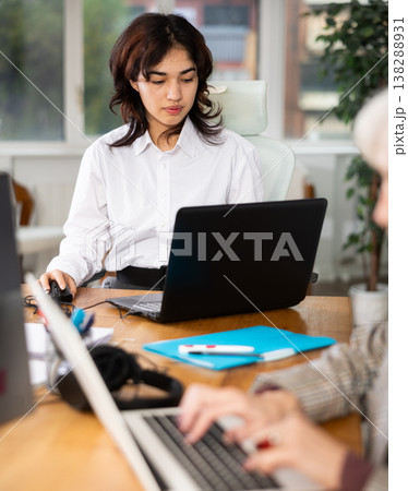 Young woman works on laptop with female colleagues Young woman works on laptop with female colleagues 138288931
