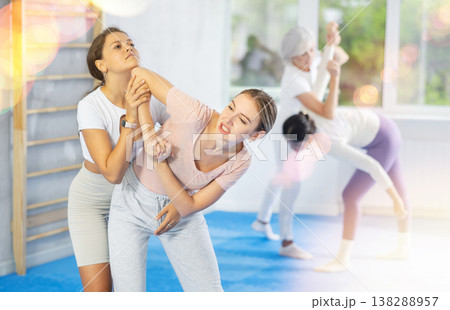 Young girl trying to escape rear grab and striking chin with elbow during self defense course Young girl trying to escape rear grab and striking chin with elbow during self defense course 138288957