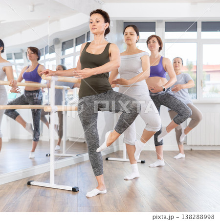 Woman mastering passe ballet move at amateur dancers rehearsal Woman mastering passe ballet move at amateur dancers rehearsal 138288998