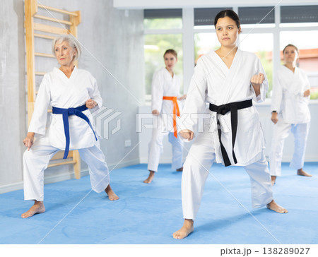 Young female karate sensei leading group of women during kata training Young female karate sensei leading group of women during kata training 138289027