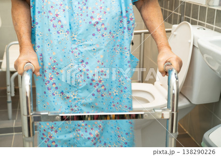 Caregiver help Asian elderly woman patient use walker and toilet bathroom handle security. 138290226