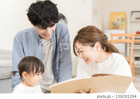 乳幼児に絵本の読み聞かせをする若い夫婦 乳幼児に絵本の読み聞かせをする若い夫婦 138291204