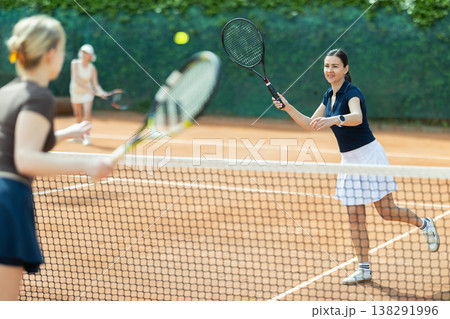 Adult woman playing doubles tennis on court Adult woman playing doubles tennis on court 138291996