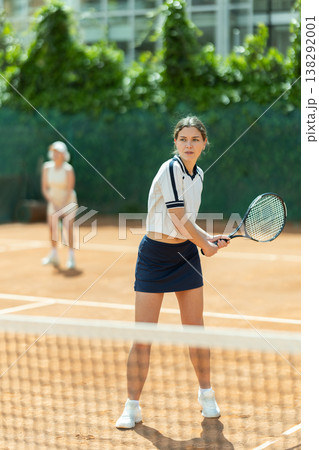Young woman playing doubles tennis on court Young woman playing doubles tennis on court 138292001