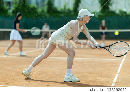 Senior female athlete plays tennis on open court with young opponent Senior female athlete plays tennis on open court with young opponent 138292052