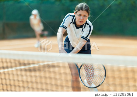 Young woman playing doubles tennis on court 138292061