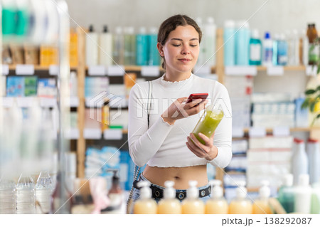 Female shopper in summer clothes chooses medicated shampoo at pharmacy Female shopper in summer clothes chooses medicated shampoo at pharmacy 138292087
