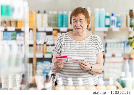 Mature woman in summer clothes buys paracetamol medicine at pharmacy 138292118