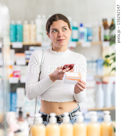 woman scans a package of pills with a mobile barcode in front of a counter in a pharmacy 138292147