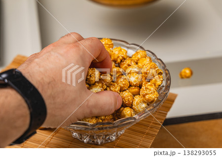 Enjoying popcorn from a glass bowl during snack time at home Enjoying popcorn from a glass bowl during snack time at home 138293055