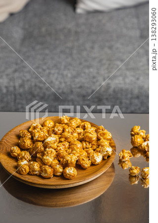 Caramel popcorn served on a wooden plate at a cozy indoor setting Caramel popcorn served on a wooden plate at a cozy indoor setting 138293060