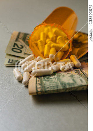 Money with pills spilled from a bottle on a gray surface 138293073