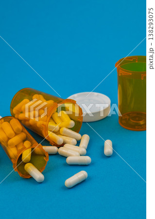 Pill bottles spilled on blue background with capsules scattered around 138293075