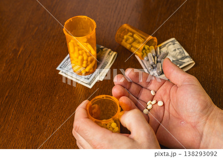 Pills and money on wooden table during daytime in a domestic setting Pills and money on wooden table during daytime in a domestic setting 138293092