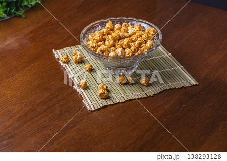 Bowl of caramel popcorn on a wooden table with a bamboo mat 138293128