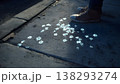 Ephemeral glowing flowers projected onto a dark sidewalk at night, with a person's shoes visible. 138293274