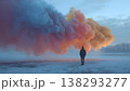 A solitary figure stands in a winter landscape as a vibrant, multi-colored smoke plume billows above. 138293277