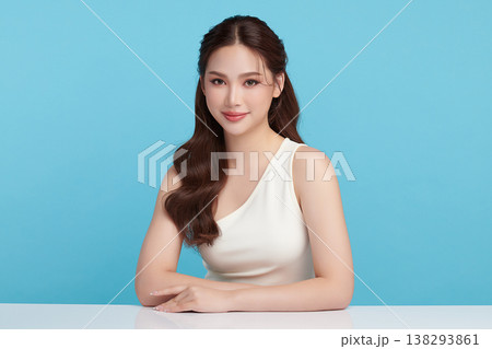 A beautiful young Asian woman with clean, fresh skin against a blue background. Skincare, facial treatment, cosmetology, beauty, and spa. An elegant portrait of an Asian woman. 138293861