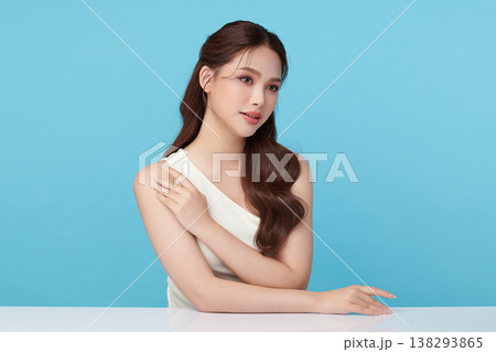 A beautiful young Asian woman with clean, fresh skin against a blue background. Skincare, facial treatment, cosmetology, beauty, and spa. An elegant portrait of an Asian woman. 138293865