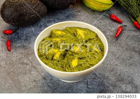Palak Paneer, an Indian spinach and cottage cheese curry, served in a bowl with fresh vegetable ingredients. 138294033