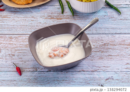 Bowl of creamy shrimp soup with a spoon on a rustic light blue wooden table with fresh chili peppers. Bowl of creamy shrimp soup with a spoon on a rustic light blue wooden table with fresh chili peppers. 138294072