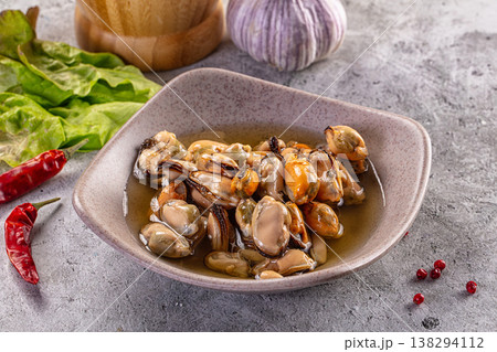 Marinated mussels in a ceramic bowl with chili and garlic on a concrete table. Marinated mussels in a ceramic bowl with chili and garlic on a concrete table. 138294112