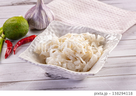 Cooked rice noodles in a white bowl with fresh lime, garlic, and chili peppers 138294118