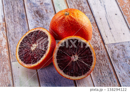 Fresh blood orange sliced in half revealing a deep red pulp on a rustic wood background. Fresh blood orange sliced in half revealing a deep red pulp on a rustic wood background. 138294122
