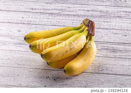 Bunch of fresh yellow bananas with green tips on a rustic white wood background. Bunch of fresh yellow bananas with green tips on a rustic white wood background. 138294128