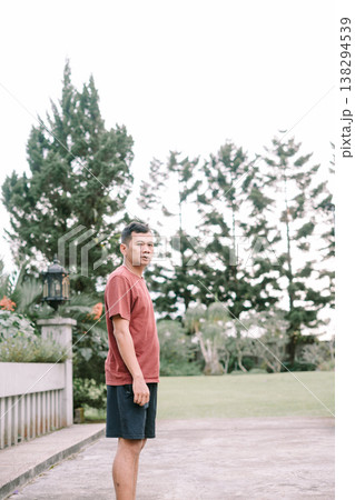 Southeast Asian man standing casually looking at camera in outdoor nature setting Southeast Asian man standing casually looking at camera in outdoor nature setting 138294539