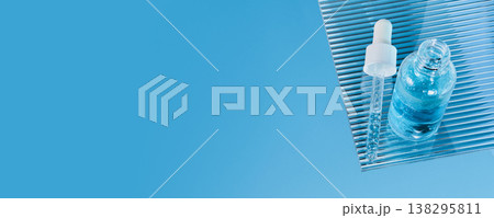 Dropper bottle with blue serum liquid on ribbed glass shelf, banner format Dropper bottle with blue serum liquid on ribbed glass shelf, banner format 138295811