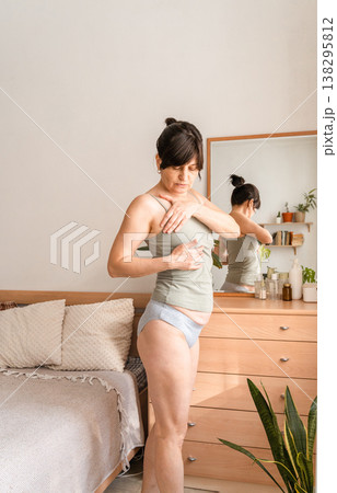 Adult woman checking her breasts for lumps, promoting areness and early detection of breast cancer at home. Taking care of your health and body Adult woman checking her breasts for lumps, promoting areness and early detection of breast cancer at home. Taking care of your health and body 138295812