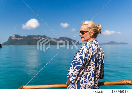 Woman standing on boat deck and looking at tropical islands in Ang Thong National Marine Park, Thailand, calm turquoise sea and clear blue sky during island cruise Woman standing on boat deck and looking at tropical islands in Ang Thong National Marine Park, Thailand, calm turquoise sea and clear blue sky during island cruise 138296018