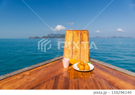 Wooden boat bow with simple food offering and drink on calm sea near islands of Ang Thong National Marine Park Thailand during sunny day Wooden boat bow with simple food offering and drink on calm sea near islands of Ang Thong National Marine Park Thailand during sunny day 138296140