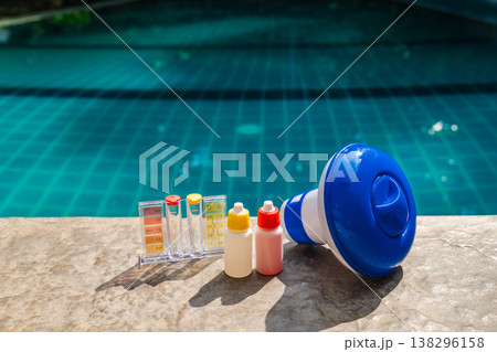 Pool water testing kit and chemical dispenser on pool edge for swimming pool maintenance and sanitation 138296158
