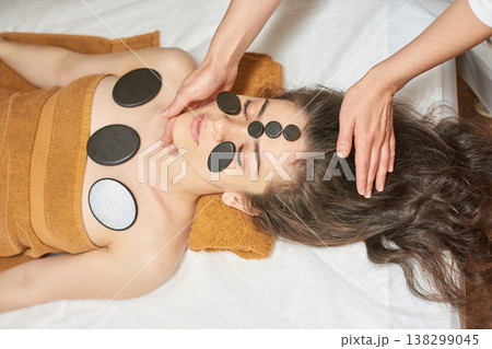 Caucasian Female Receiving Hot Stone Massage Therapy For Relaxation And Rejuvenation At Spa, Young Caucasian Female Receiving Hot Stone Massage Therapy For Relaxation And Rejuvenation At Spa, Young 138299045