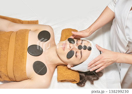 Young Caucasian Woman Relaxing With Hot Stone Therapy At Spa For Rejuvenation And Stress Relief 138299230
