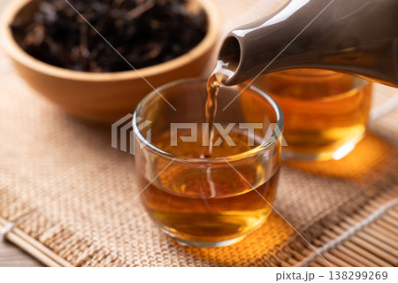 Pouring hot black tea from teapot into a glass cup, Asian healthy beverage culture Pouring hot black tea from teapot into a glass cup, Asian healthy beverage culture 138299269