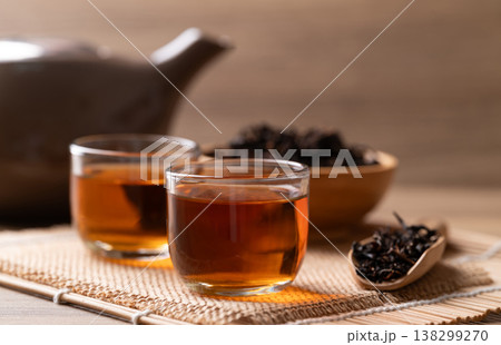 Hot black tea in a glass cup with dry tea leaves, Asian healthy beverage culture Hot black tea in a glass cup with dry tea leaves, Asian healthy beverage culture 138299270
