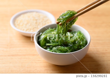 Fresh Japanese seaweed salad (Chuka Wakame) being picked up with chopsticks from a bowl  138299281