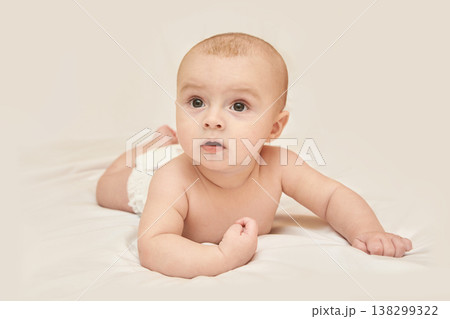 Caucasian Infant Lying On Stomach With Curious Expression On Soft White Bedding In Calm Setting Caucasian Infant Lying On Stomach With Curious Expression On Soft White Bedding In Calm Setting 138299322