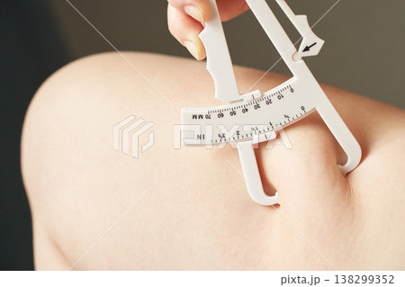 Female hand using skinfold caliper on arm for body fat measurement and fitness assessment Female hand using skinfold caliper on arm for body fat measurement and fitness assessment 138299352