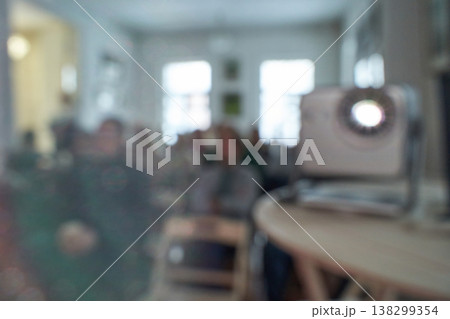 Blurred group of adults in a room with projector and unfocused background 138299354