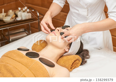 Caucasian Female Receiving Hot Stone Therapy At Spa With Relaxing Atmosphere For Wellness 138299379