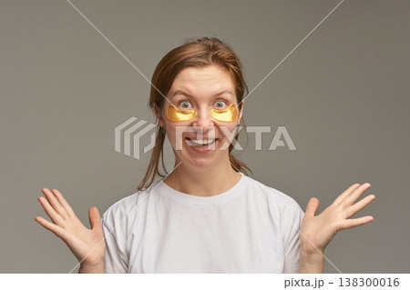 Caucasian female adult with eye masks smiling cheerfully in white t-shirt against neutral Caucasian female adult with eye masks smiling cheerfully in white t-shirt against neutral 138300016
